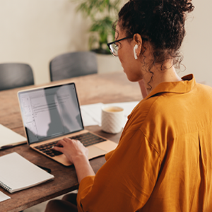 Woman sitting at a table conducting research on her laptop.